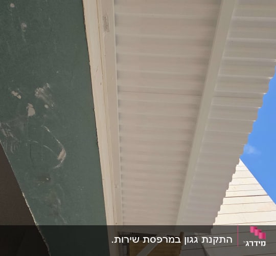 גגון אלומיניום לבן מותקן על קיר חיצוני של בניין